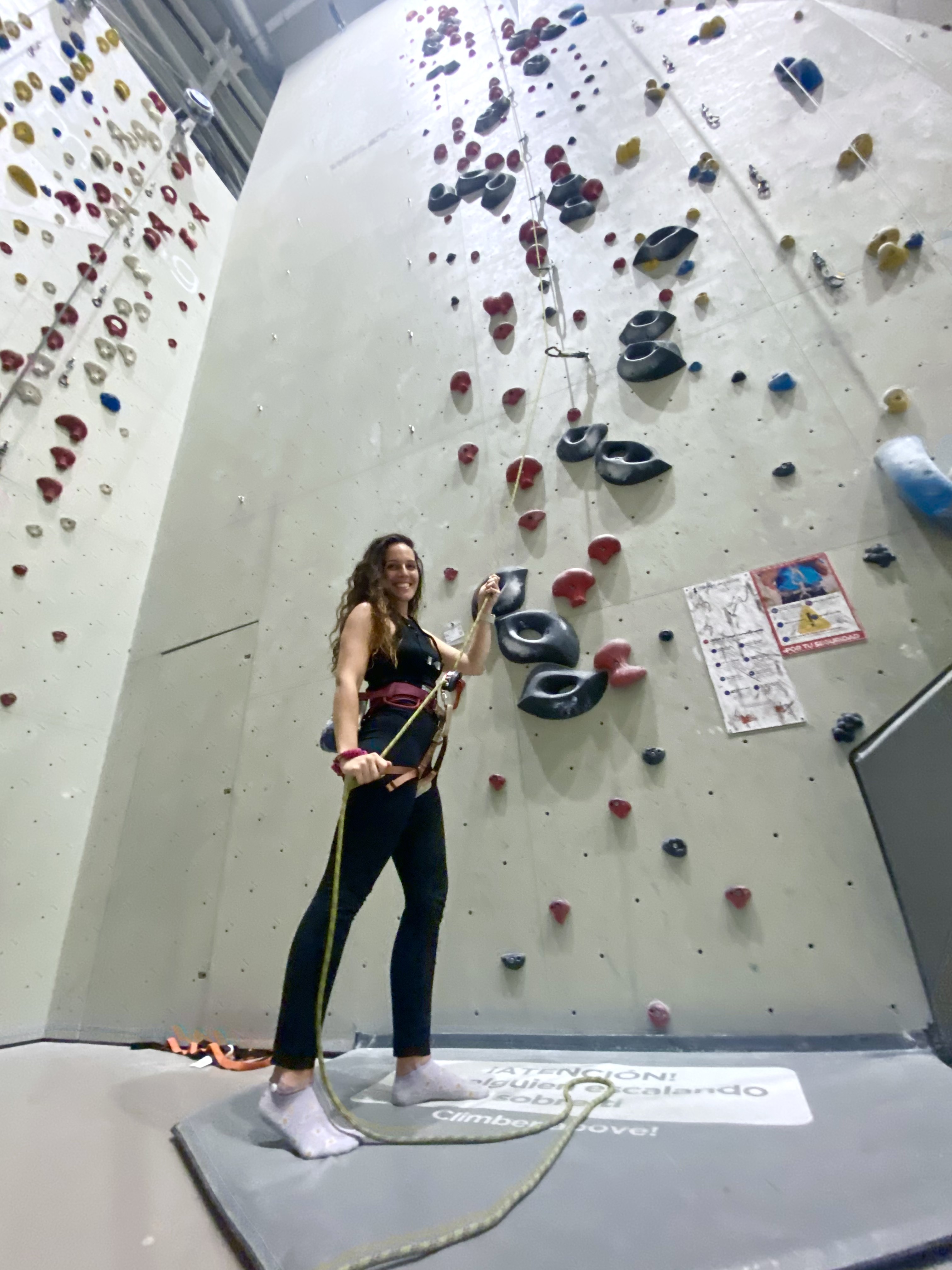 Elena en un rocódromo, junto a una pared de escalada